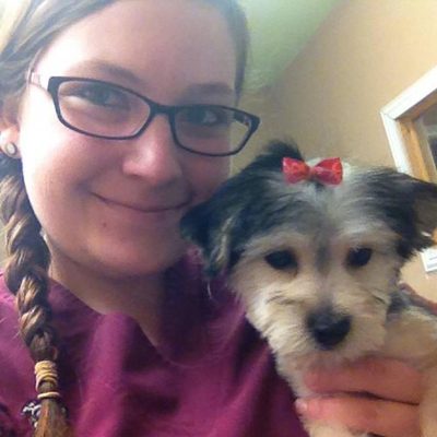Rachel holding a small black-and-white dog wearing a red bow